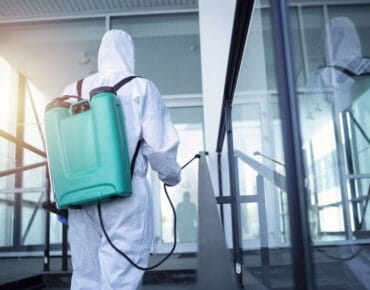 Man with tank reservoir on his back spraying disinfectant to stop corona virus.